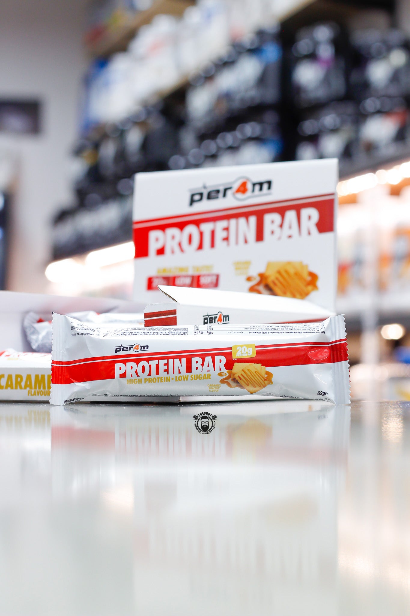 Per4m Protein Bar, Caramel Biscuit flavour (20g protein), high protein low sugar bar displayed in front of open retail box in supplement store.