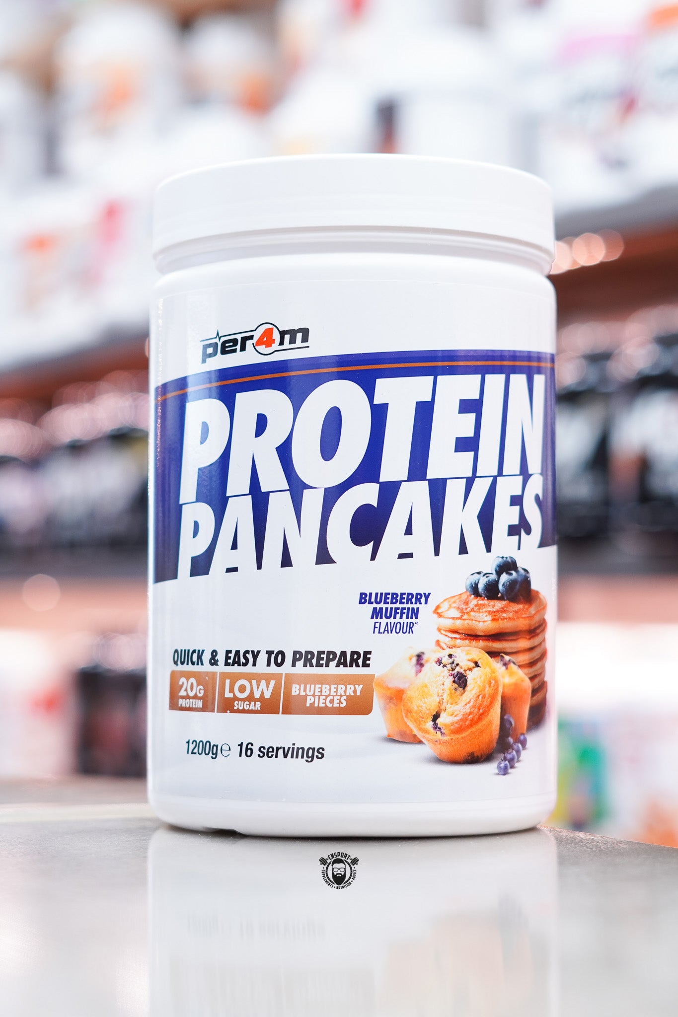 White tub of Per4m Protein Pancakes, Blueberry Muffin flavour, showing stack of pancakes and muffin with blueberries on the label.