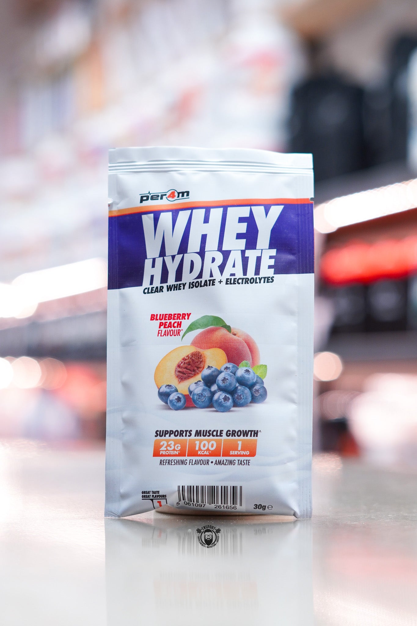Per4m Whey Hydrate 30g sample sachet, Blueberry Peach flavour, clear whey isolate with electrolytes, displayed on counter in supplement store.