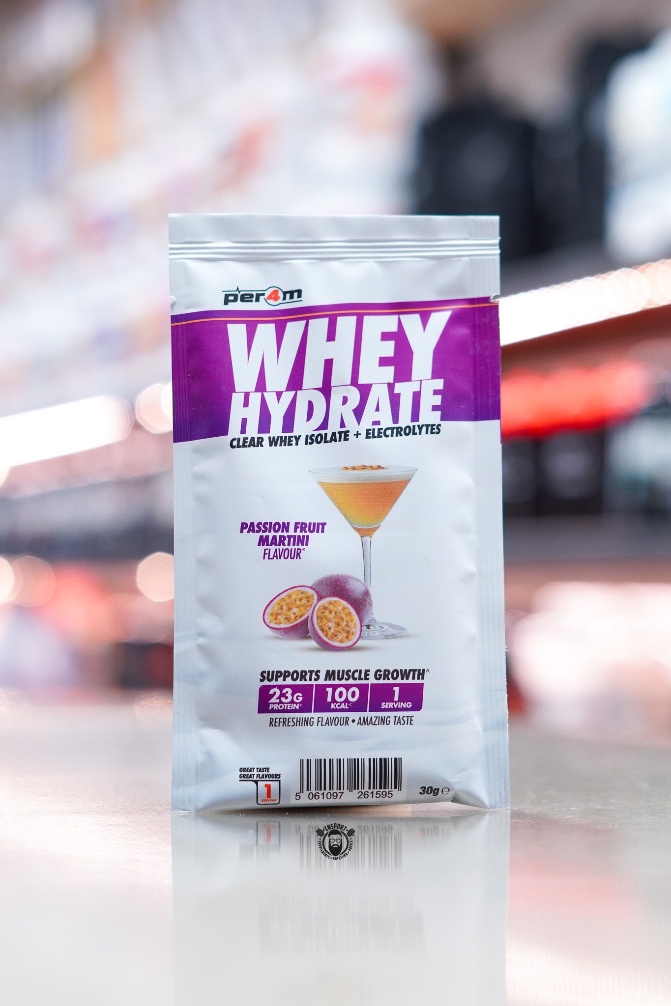 Per4m Whey Hydrate 30g sample sachet, Passion Fruit Martini flavour, clear whey isolate with electrolytes, displayed on counter in supplement store.