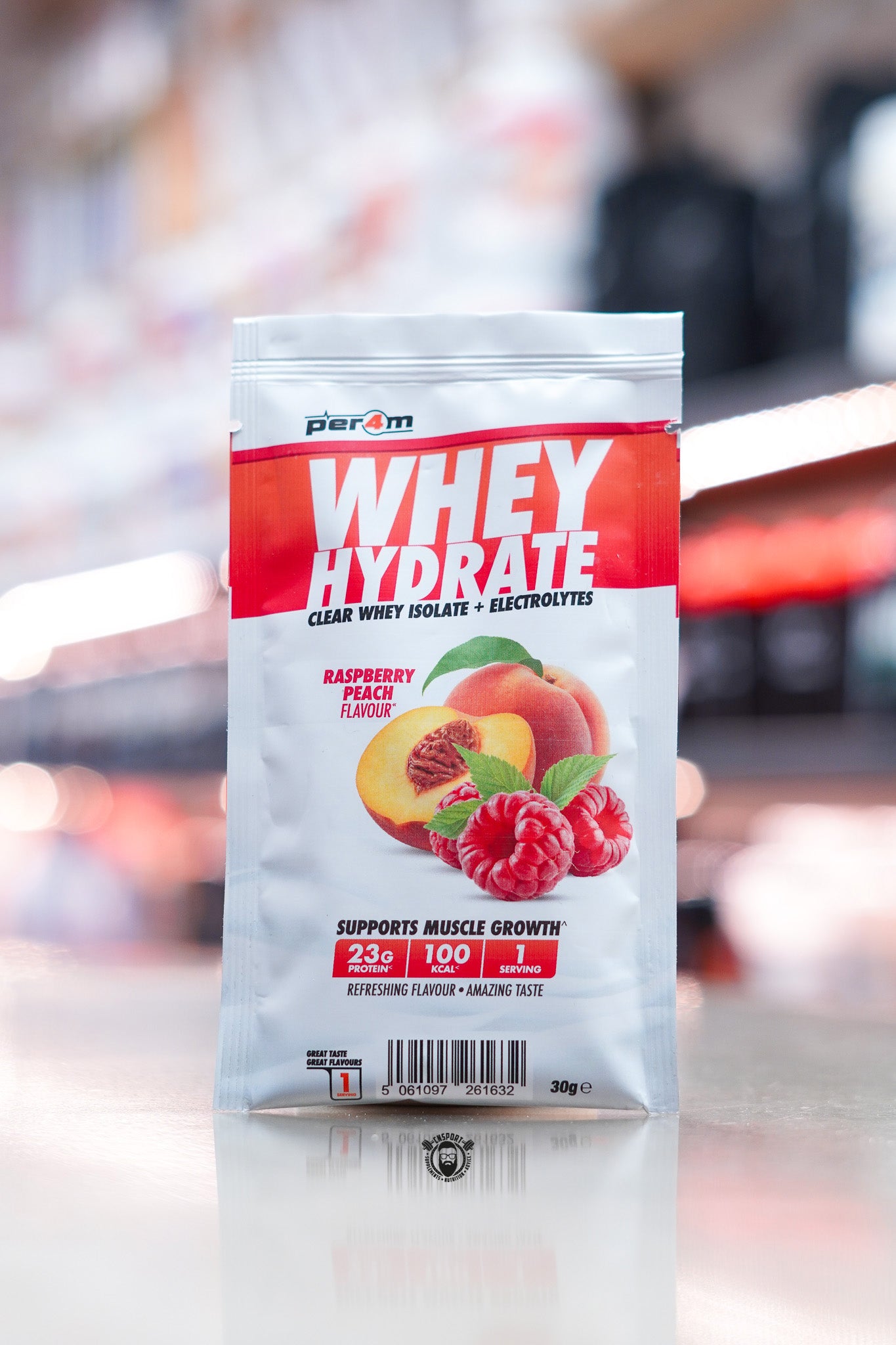 Per4m Whey Hydrate 30g sample sachet, Raspberry Peach flavour, clear whey isolate with electrolytes, displayed on counter in supplement store.