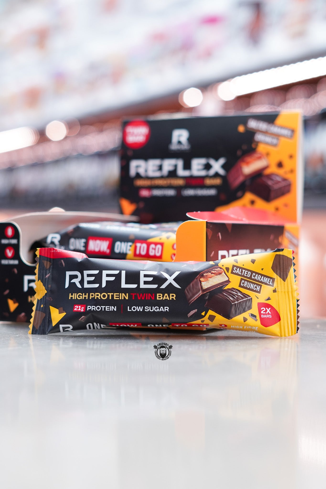 Reflex Nutrition High Protein Twin Bar in Salted Caramel Crunch flavor, 21g protein and low sugar, presented in its two-bar wrapper with box display.