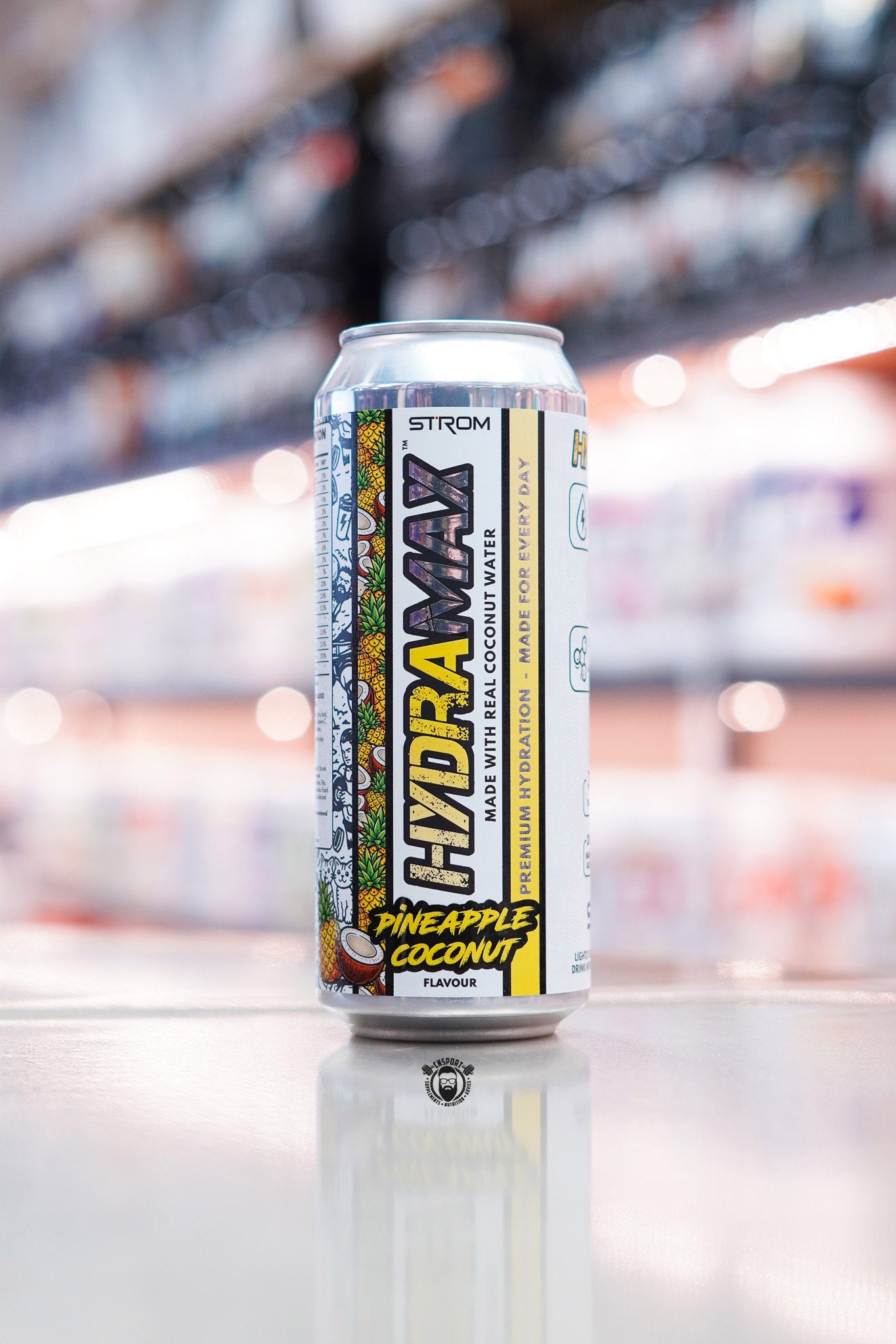Strom HydraMax Pineapple Coconut hydration drink can made with real coconut water on retail counter with blurred supplement store background