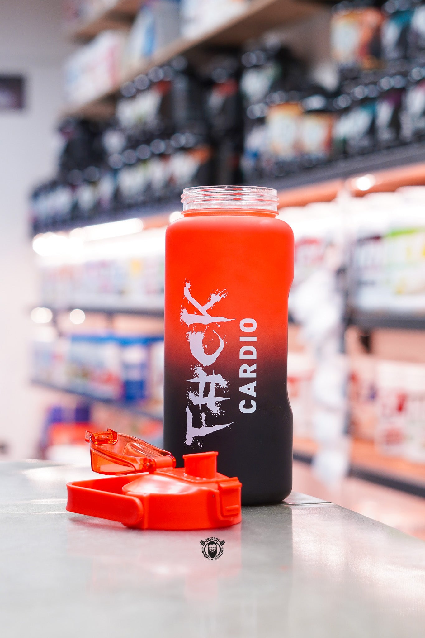 TWP Cardio 2L hydration water bottle in a red and black frosted finish with flip-top lid removed, displayed on a supplement store counter.
