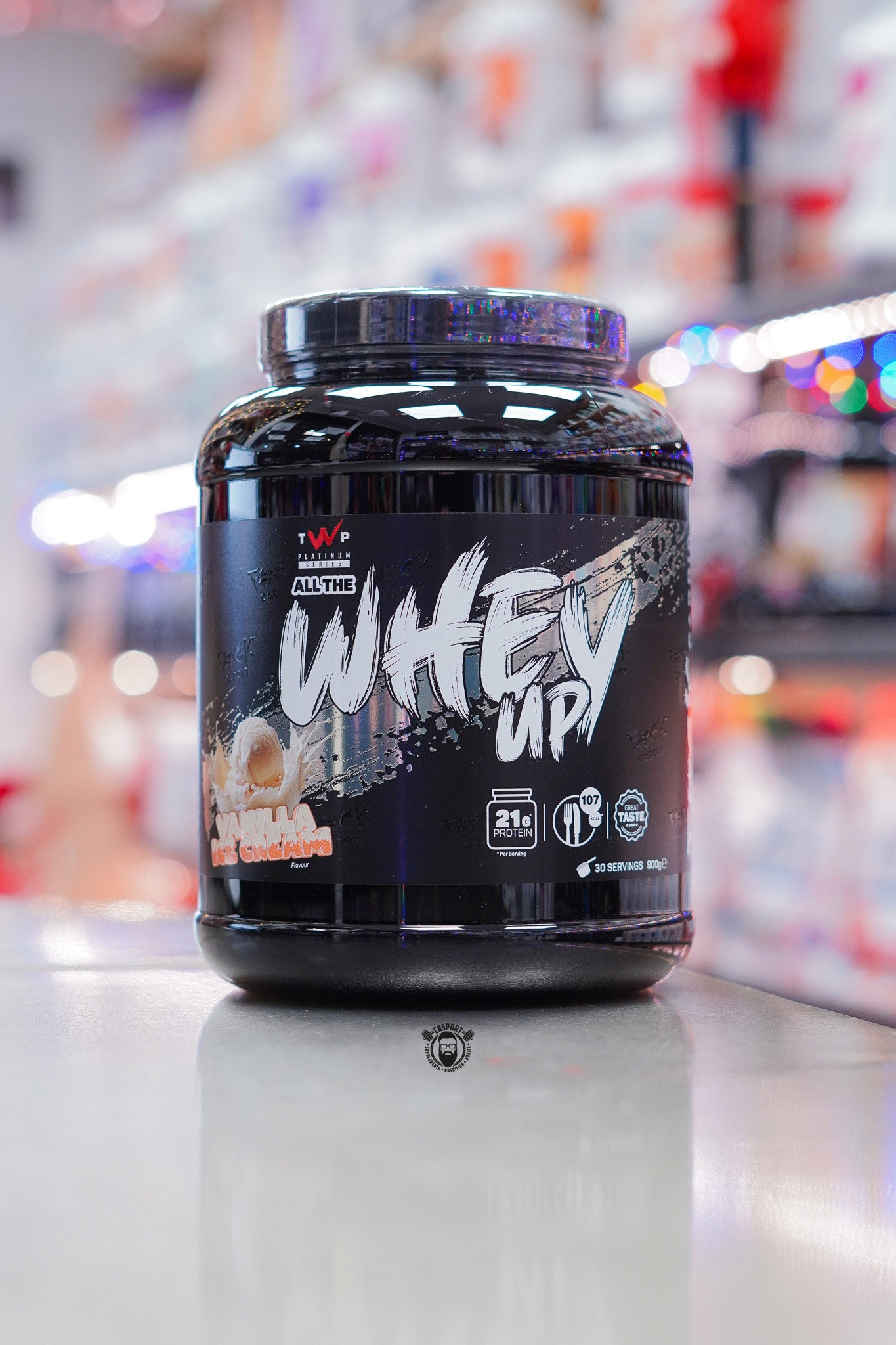 TWP Platinum Series All The Whey Up protein powder in Vanilla Ice Cream flavour, 900g black tub photographed in a supplement shop environment.