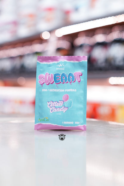 Single-serving 15g sample sachet in light blue and pink packaging with cotton candy illustration and AstraGin logo, positioned upright on a store counter with blurred supplement tubs in the background.